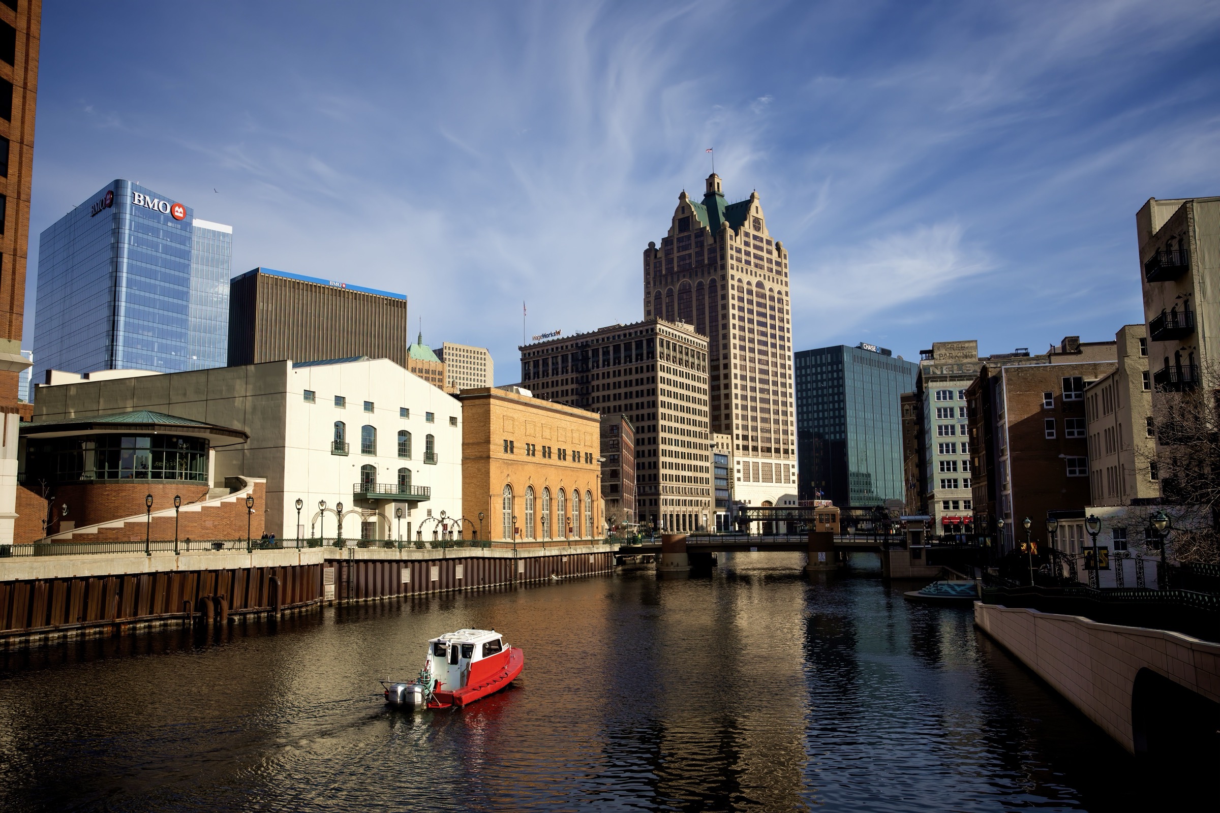 Milwaukee Riverwalk and downtown skyline with a boat on the river