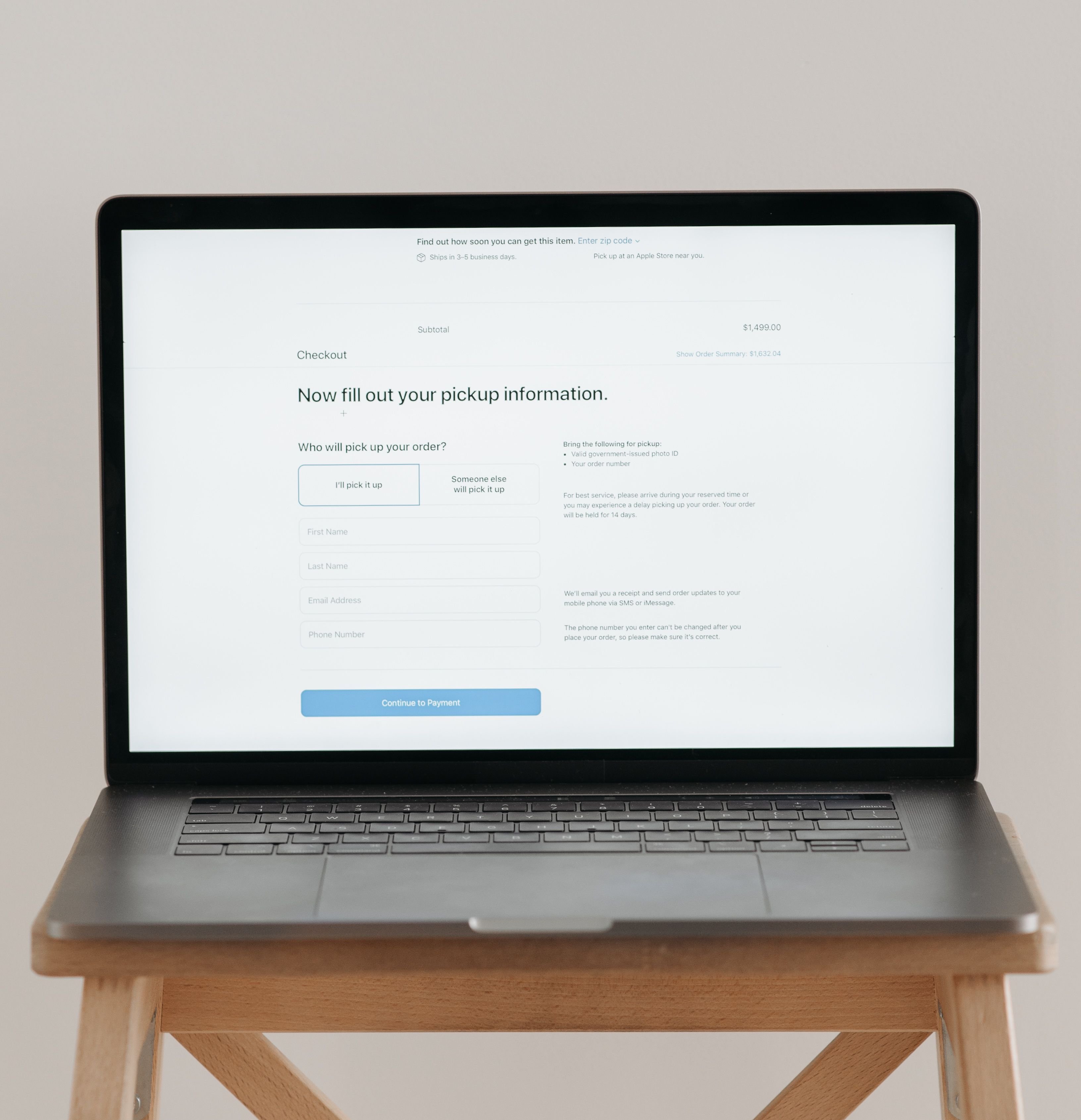 Laptop showing a checkout form on a wooden stool